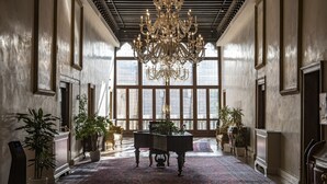 A grand lobby with a large chandelier, potted plants, and a classic wooden table.