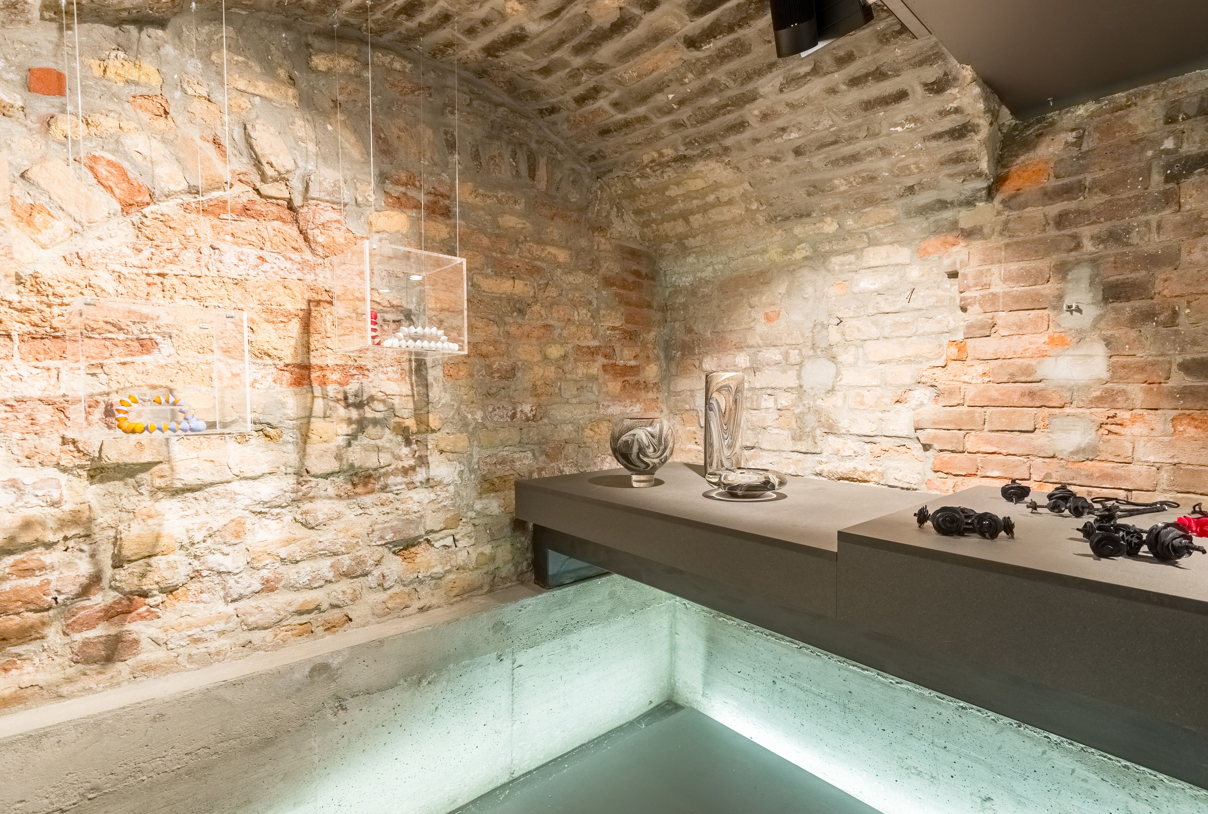 Una habitación con paredes de piedra, una barra moderna y una vitrina de cristal.
