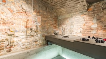 Una habitación con paredes de piedra, una barra moderna y una vitrina de cristal.