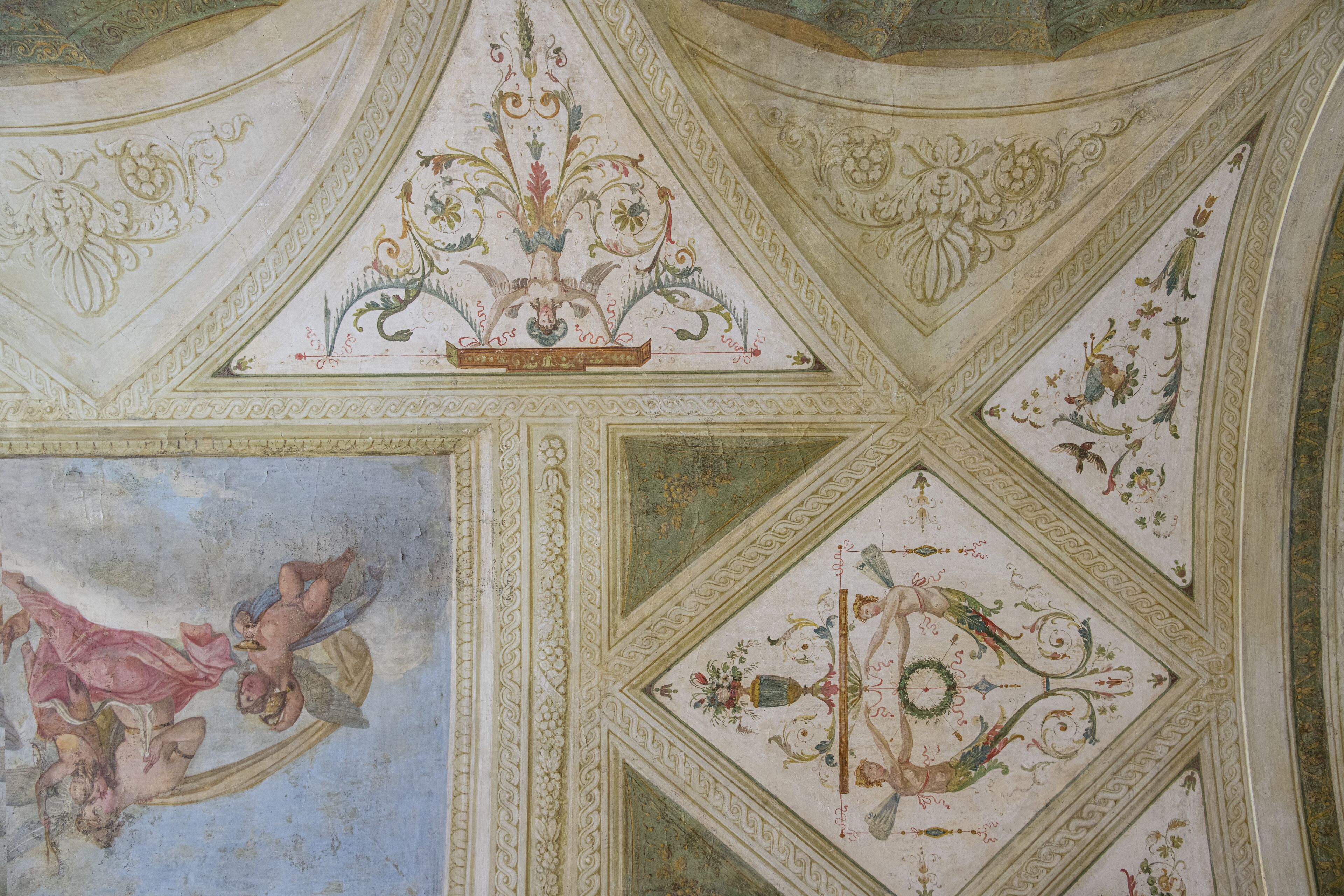 A ceiling with intricate floral and geometric patterns, including a central medallion and a fresco of cherubs.