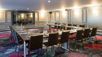 A conference room with a long table, chairs, and a carpeted floor.