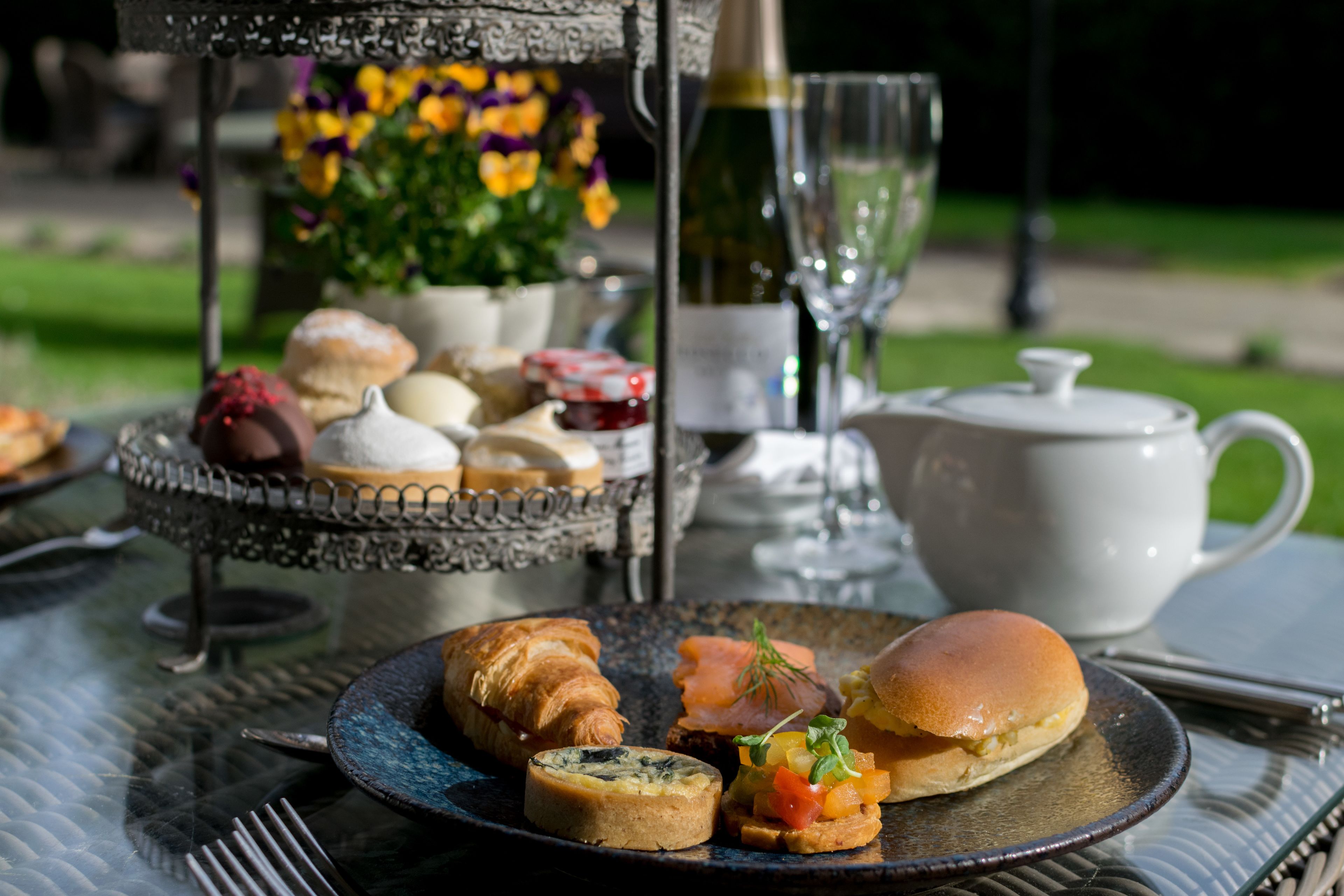 A table set with pastries, a teapot, and a bottle of wine, suggesting a tea service.