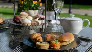 A table set with pastries, a teapot, and a bottle of wine, suggesting a tea service.