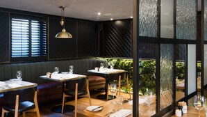 A restaurant with booths, tables, and a view of greenery through large windows. - Hotel Du Vin Stratford Upon Avon (Stratford-upon-Avon)