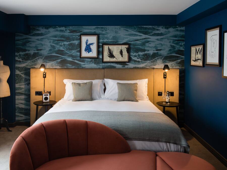 A hotel room with a bed, two bedside tables, a lamp, and a chair.