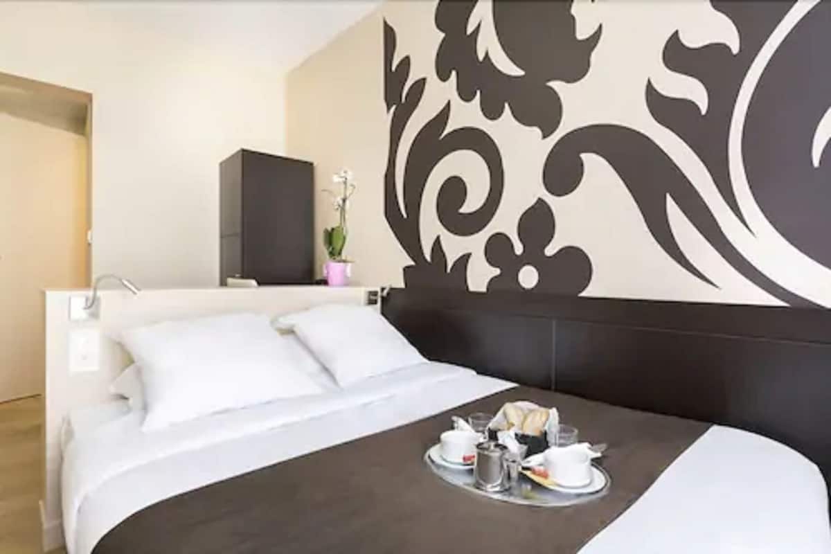 Una habitación de hotel moderna con una cama grande, un muro decorativo y una bandeja con alimentos para el desayuno.