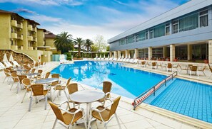 Una piscina cubierta, una piscina al aire libre, sombrillas, tumbonas