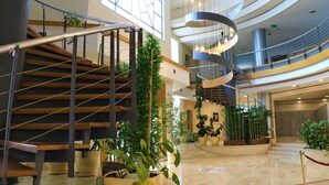 Un interior moderno con una escalera de madera, varios niveles y plantas en macetas.