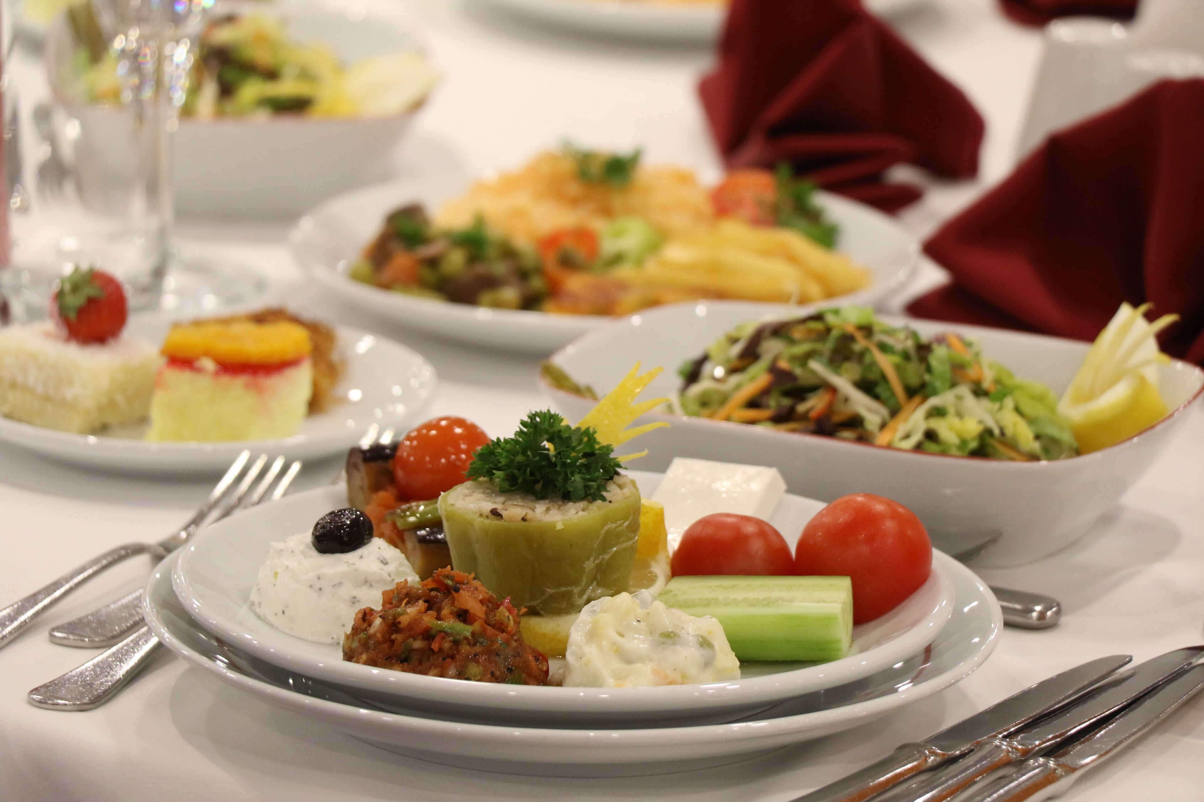 A variety of dishes on a table, including a salad, a fruit tart, and a dish with a dollop of cream.