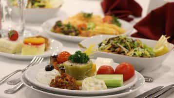 A variety of dishes on a table, including a salad, a fruit tart, and a dish with a dollop of cream.
