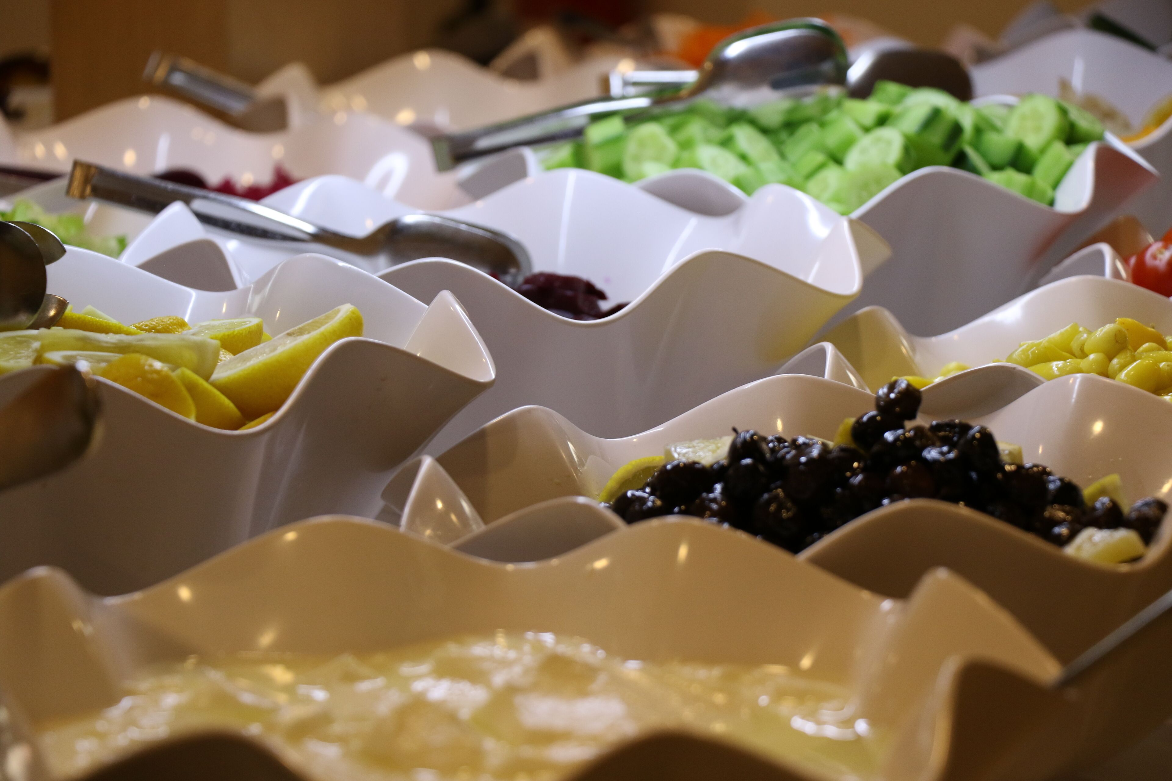 Un bufé con diferentes alimentos servidos en recipientes blancos.