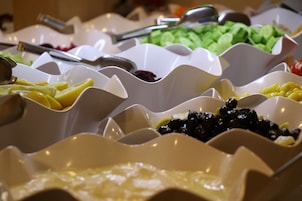 A buffet with various food items in white bowls.