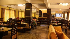 A hotel lobby with multiple dining areas, a sofa, and a TV screen. - Banex Hotel and Suites (Lagos)