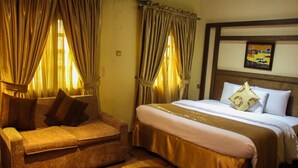 A hotel room with a bed, a sofa, and curtains. - Banex Hotel and Suites (Lagos)