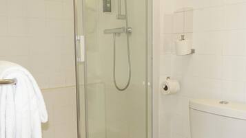 A bathroom with a glass shower enclosure, a toilet, and a towel rack.