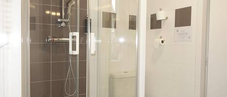 A modern bathroom with a glass-enclosed shower, a toilet, and a hand dryer.