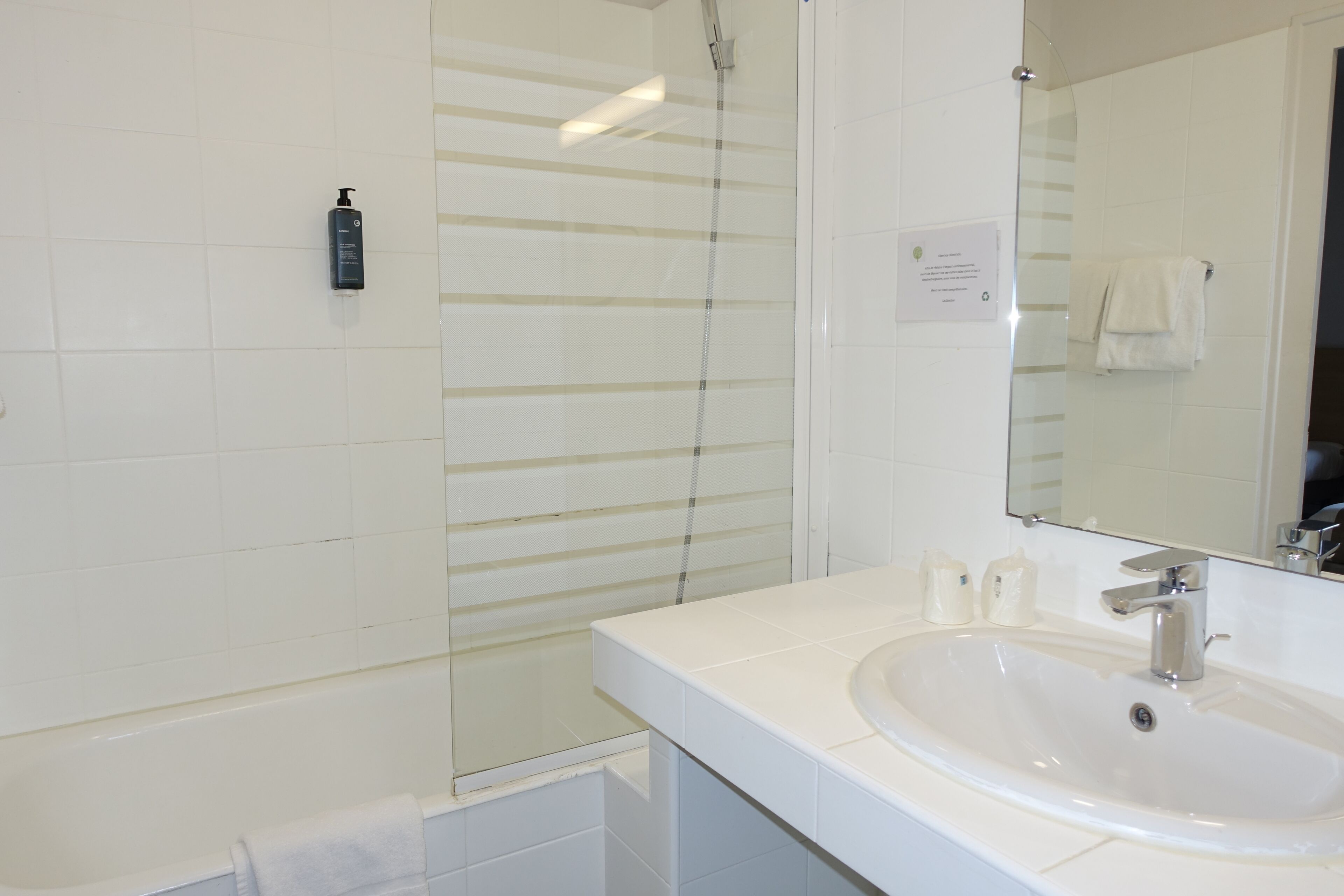 A bathroom with a white sink, a mirror, and a shower.
