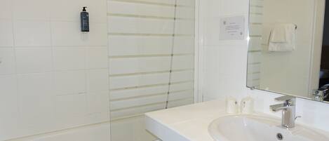 A bathroom with a white sink, a mirror, and a shower.