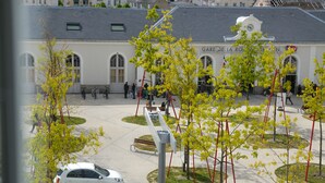 A courtyard with a white building featuring arched windows and a clock tower. - Hôtel de la Gare (La Roche-sur-Yon)