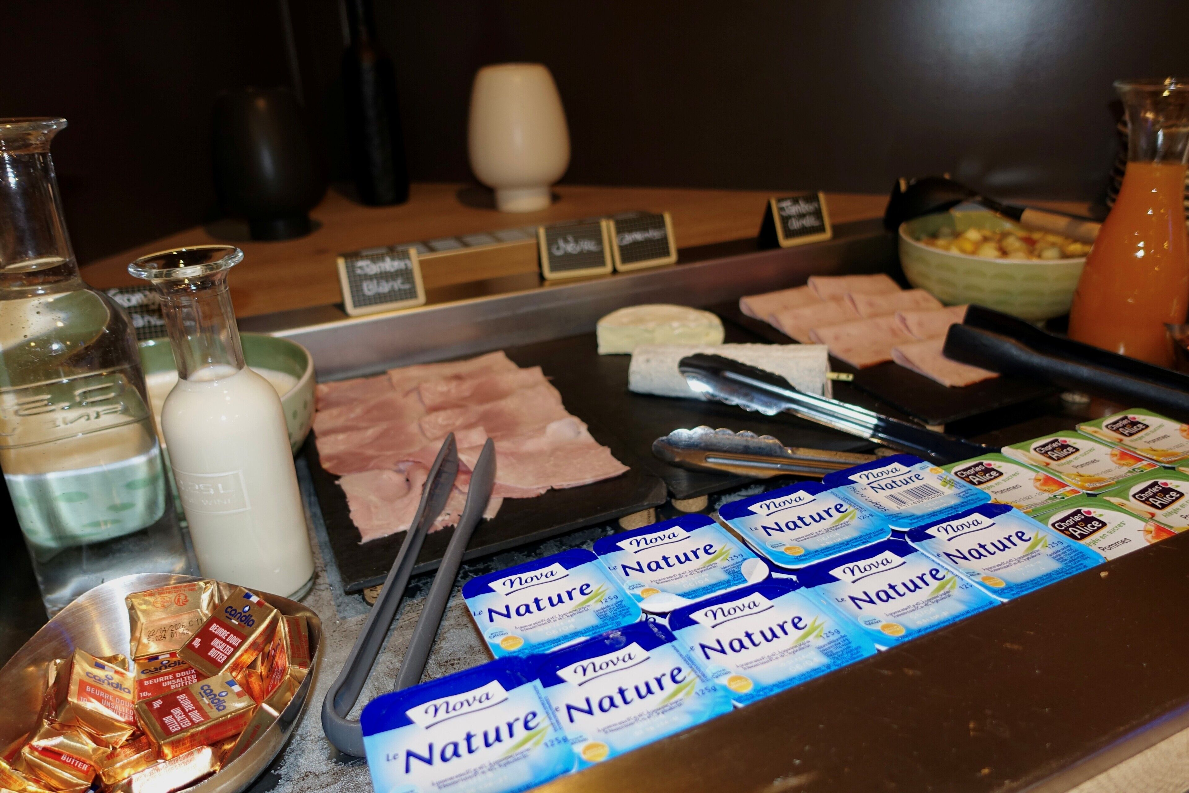 A buffet with various food items and condiments, including cheese, meats, and packaged snacks.