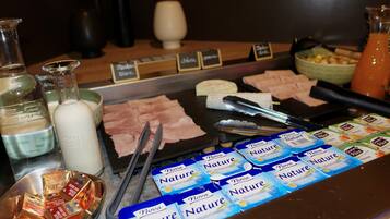A buffet with various food items and condiments, including cheese, meats, and packaged snacks.