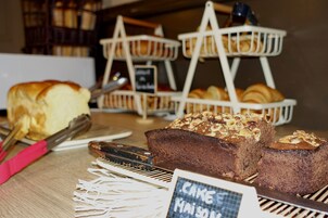 Mostrador de panadería con diversos productos horneados, incluyendo un cartel de tarta y un par de tijeras sobre una superficie de madera.