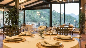 A dining area with round tables set for a meal, featuring woven placemats, white napkins, and clear glassware. - Calerilla Hotel (La Iruela)