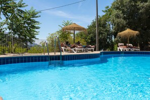 Una piscina al aire libre de temporada, sombrillas