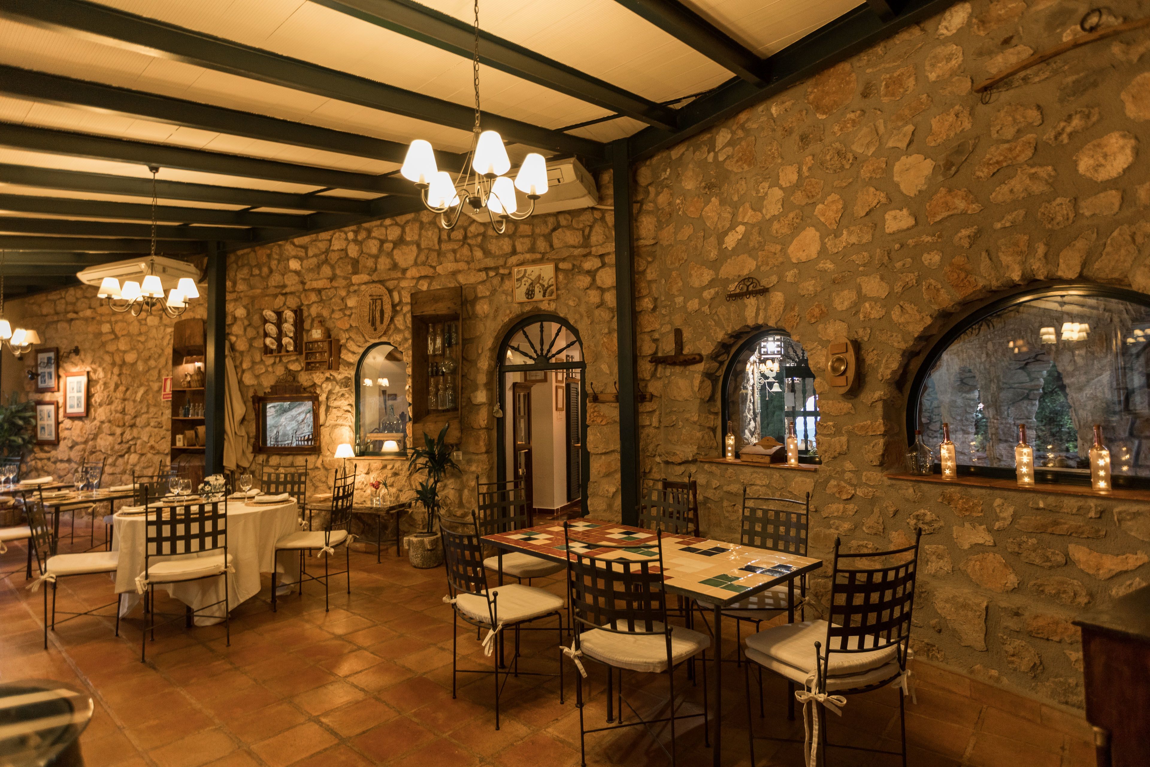 Un restaurante con paredes de piedra, muebles de madera y una araña.