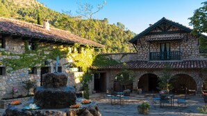A stone building with a tiled roof, outdoor seating, and a fountain. - Calerilla Hotel (La Iruela)