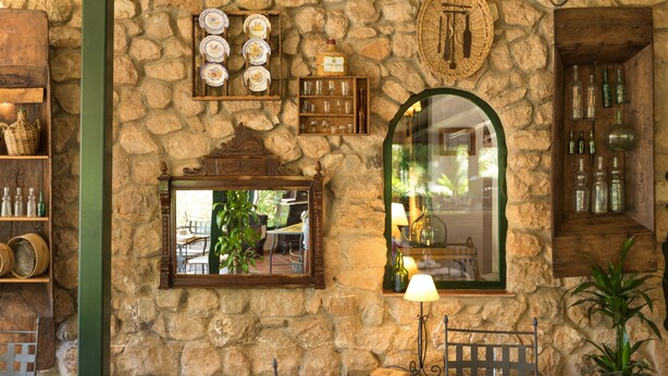 A stone wall with shelves holding plates, glasses, and bottles. - Calerilla Hotel (La Iruela)