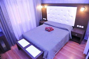 A modern bedroom with a tufted headboard, a bedside table with a lamp, and a bed with striped bedding.
