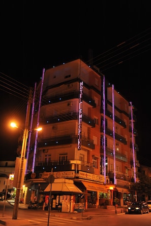 A multi-story hotel with balconies, a ground-level restaurant, and illuminated signage.
