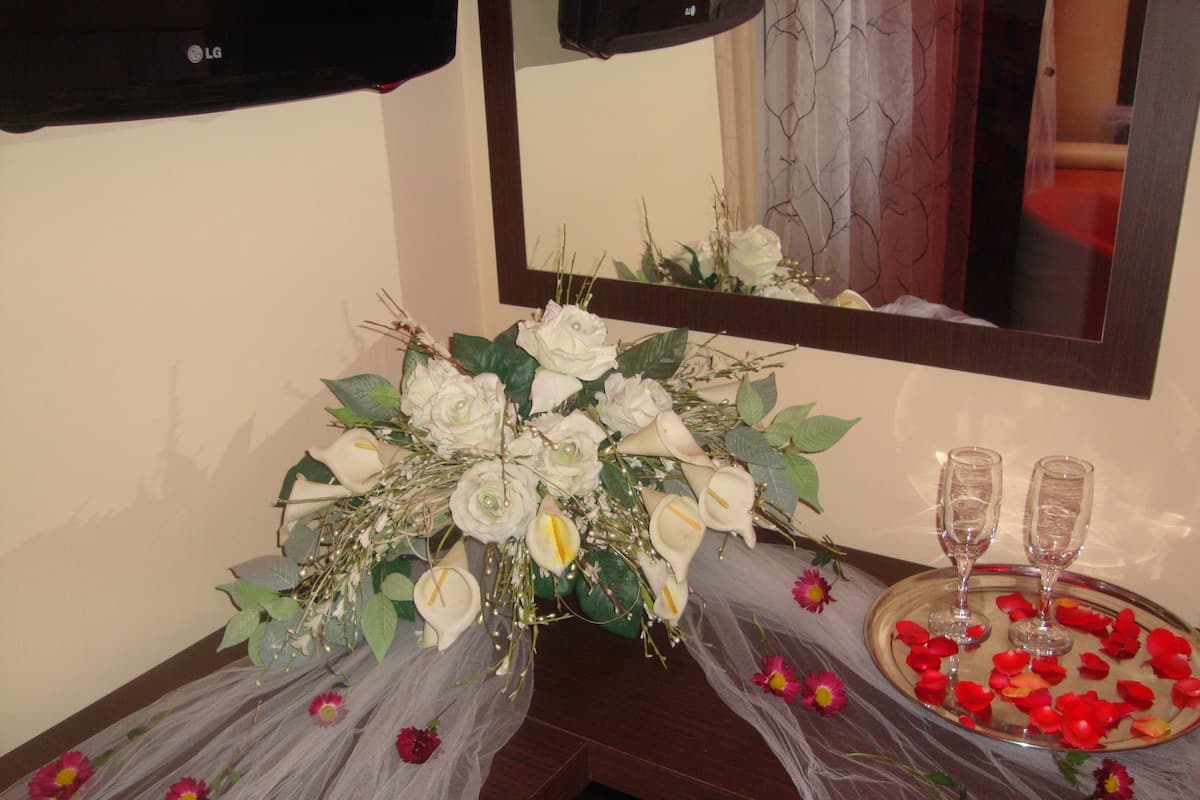 Ein Badezimmer mit Spiegel, einem Strauß weißer Blumen und zwei Gläsern auf einem Tablett mit Rosenblättern.