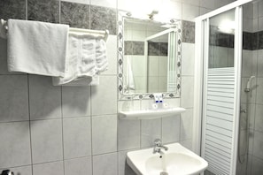 A bathroom with a white sink, a mirror, and a shower.