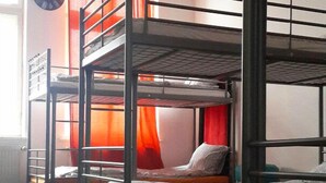 A dormitory room with bunk beds, a clock on the wall, and a window with curtains. - Art Hostel (Kraków)