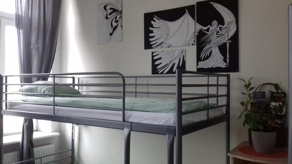 A bunk bed room with a window, curtains, and wall art including a winged figure. - Art Hostel (Kraków)