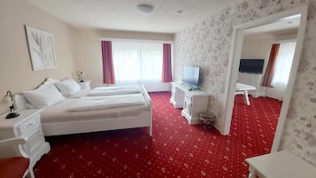 Una camera d'albergo con un letto grande, una televisione, una scrivania e un tappeto rosso.