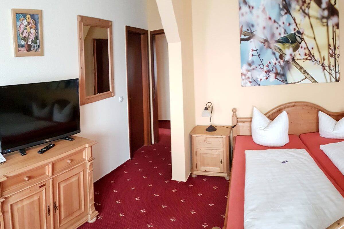 Habitación de hotel con cama, televisión, escritorio, sofá rojo y una pequeña mesa redonda.