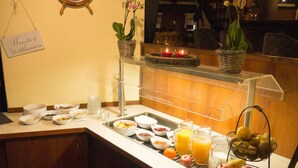 A breakfast buffet with various food items, a fruit basket, and a sign that reads "Herzlich Willkommen". - Hotel Der Muehlenhof (Westerdeichstrich)