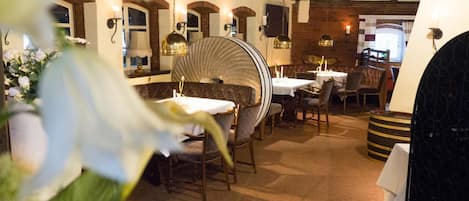 Un restaurante con una decoración rústica, que presenta paredes de ladrillo visto, vigas de madera y una combinación de mesas redondas y rectangulares.