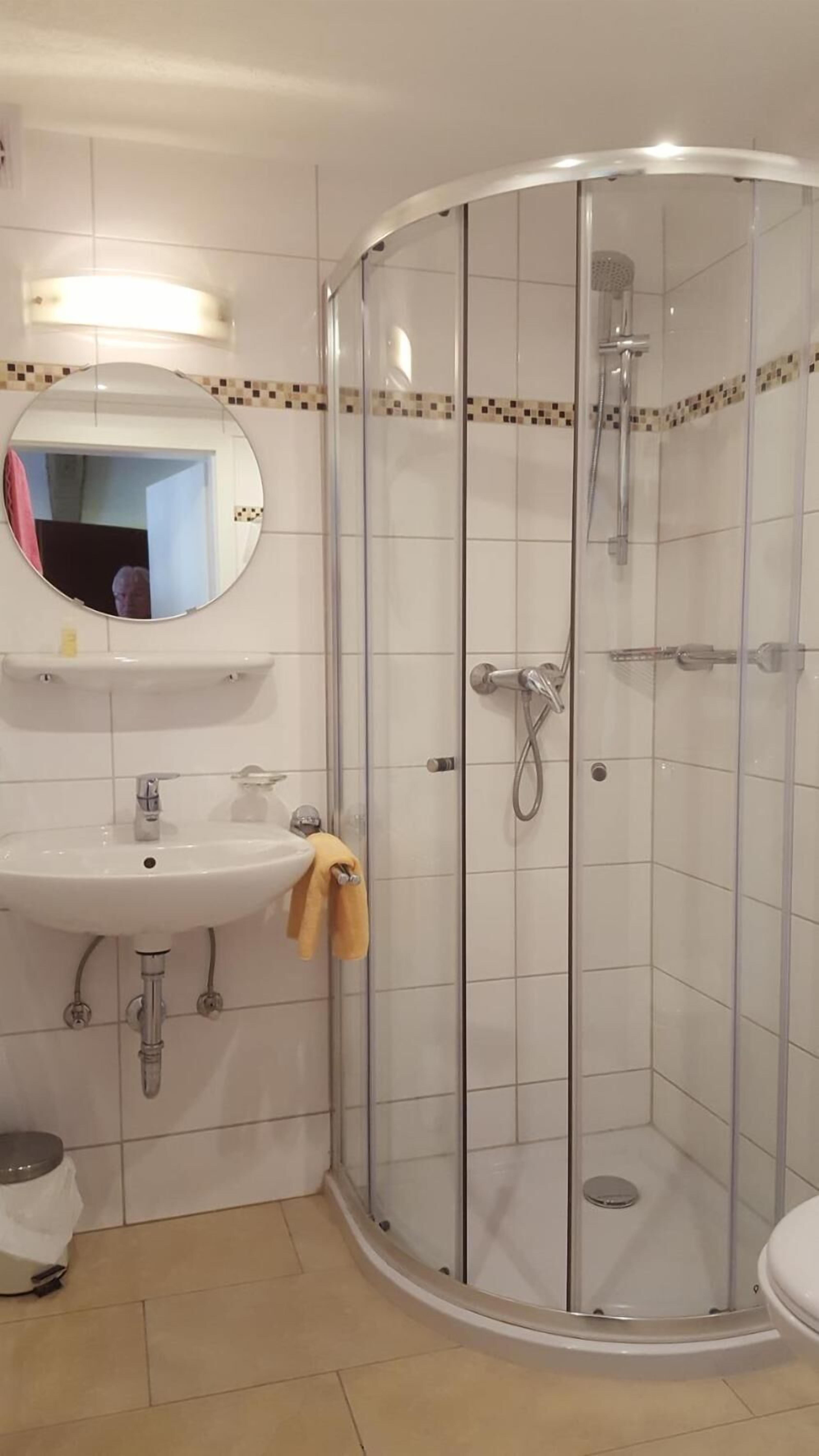 Un baño con ducha de vidrio, un lavabo con espejo y un inodoro.