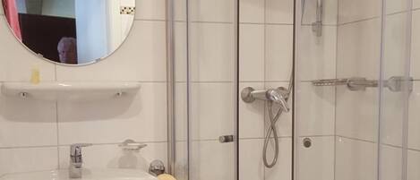A bathroom with a glass-enclosed shower, a sink, and a mirror.