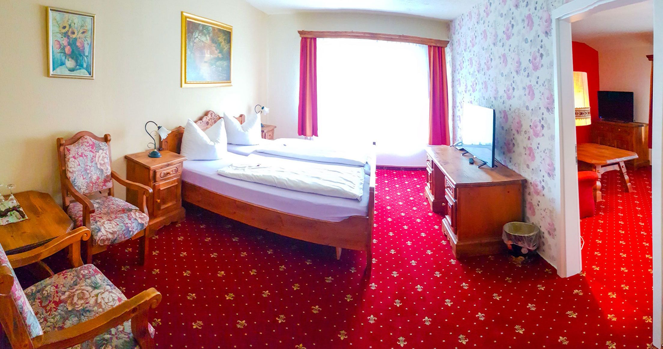 A hotel room with a bed, a desk, a chair, and a television.