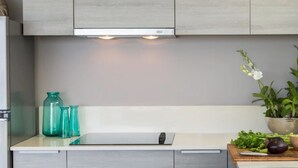 A modern kitchen with grey cabinets, a white countertop, and a sink. There are green plants and vegetables on the counter. - Villa Nuéa at Comoon Boutique Villas (Koh Samui)
