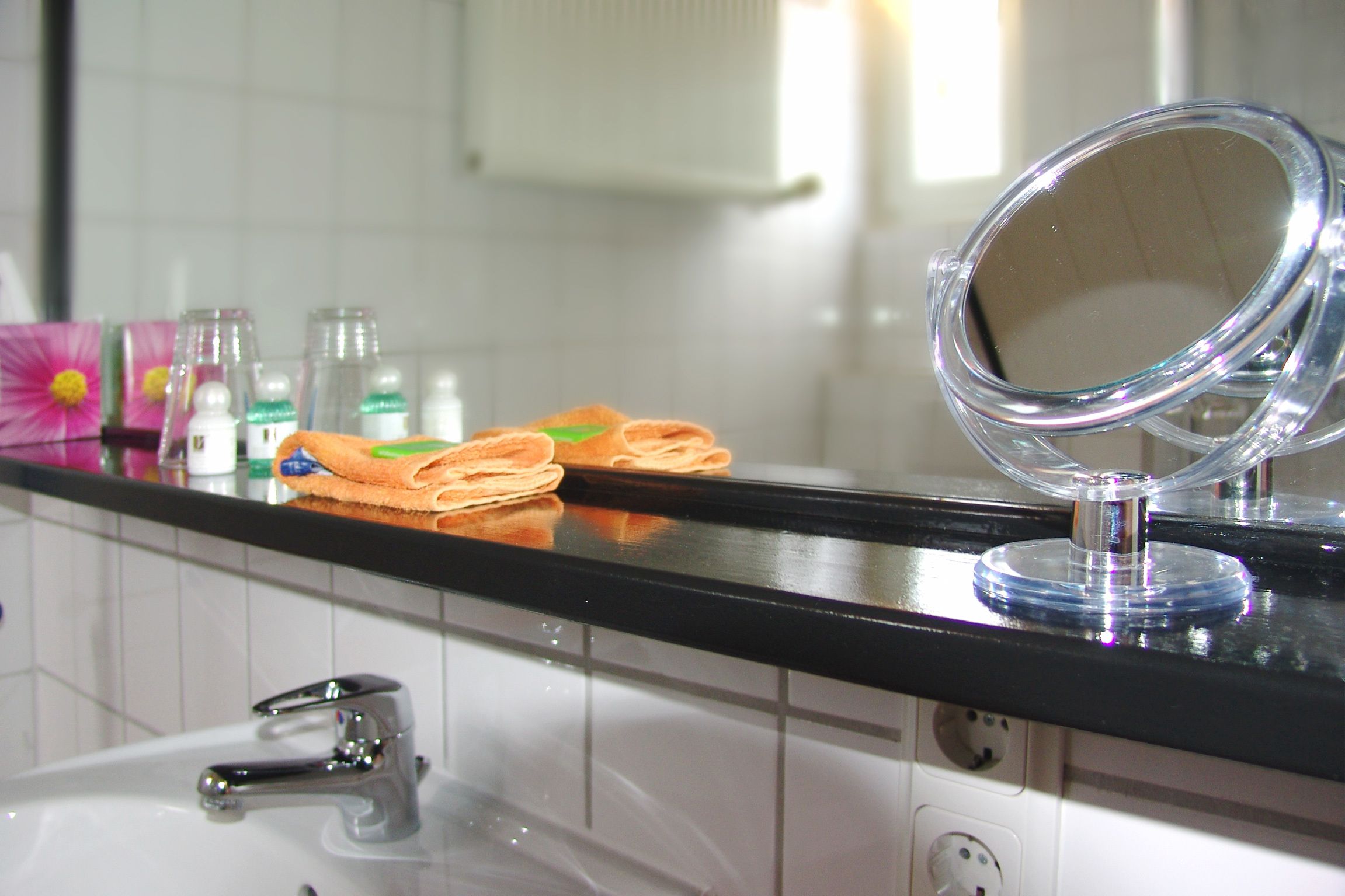 Un baño con encimera negra, un lavamanos y un espejo.
