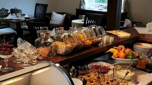 A buffet setup with various food items and a dining area with chairs and a table. - Landhaus Uttum (Krummhoern)