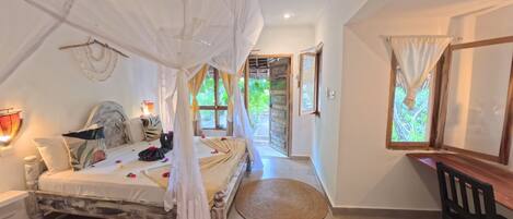 Ein Schlafzimmer mit Baldachinbett, Schreibtisch und Blick ins Freie.