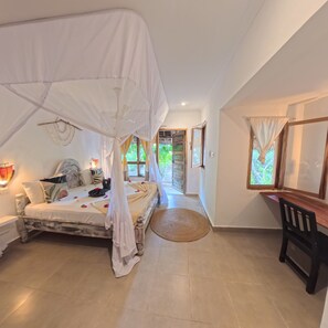 A bedroom with a canopy bed, a desk, and a view of the outdoors. - Paje By Night (Paje)
