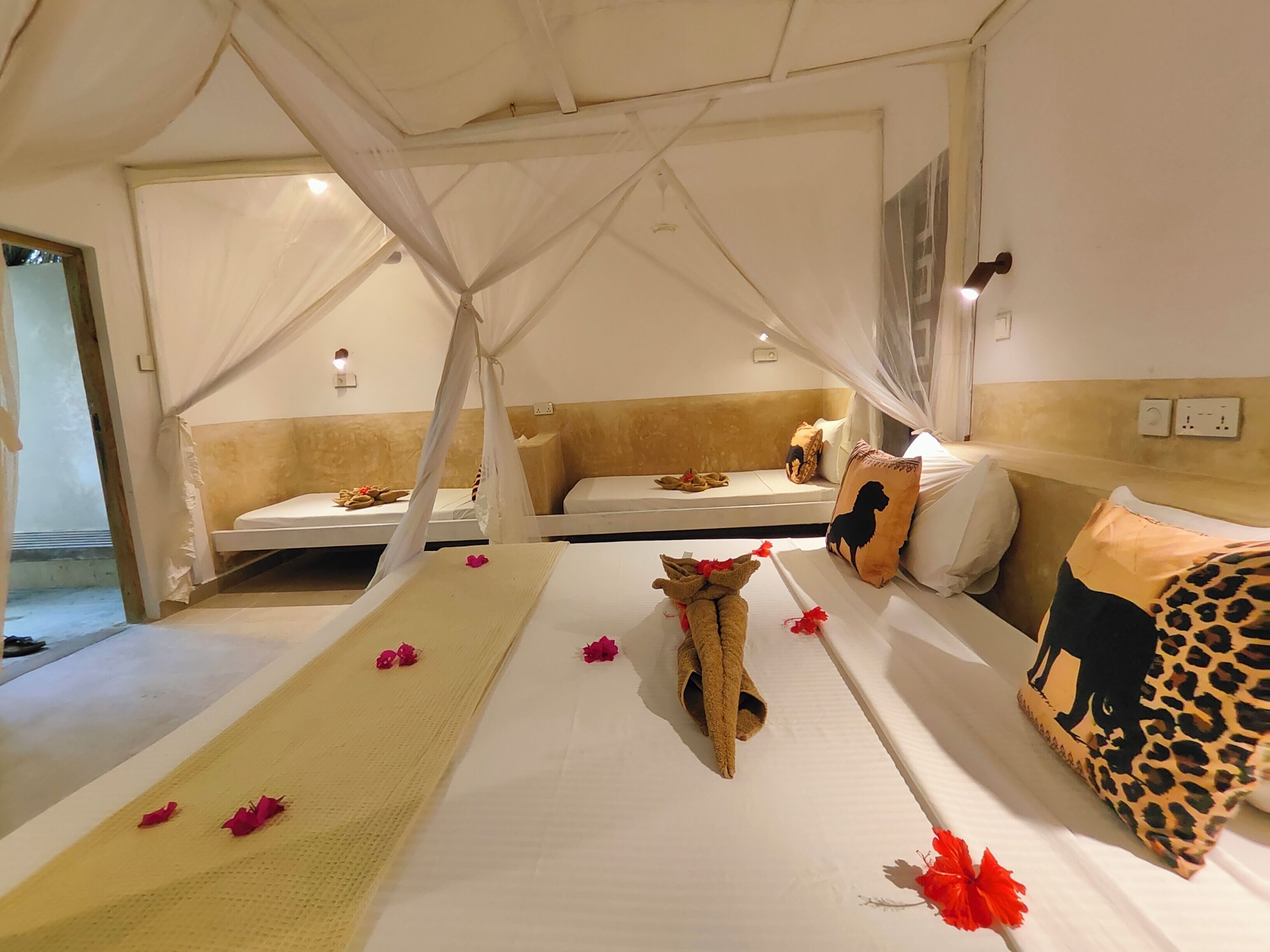 Habitación de hotel con cama, banco y dosel.